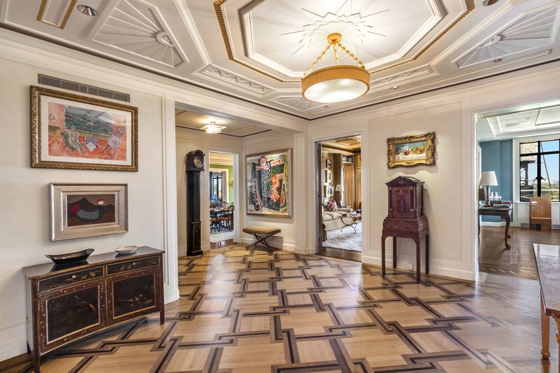 A foyer with wooden floors that have a geometric pattern. 