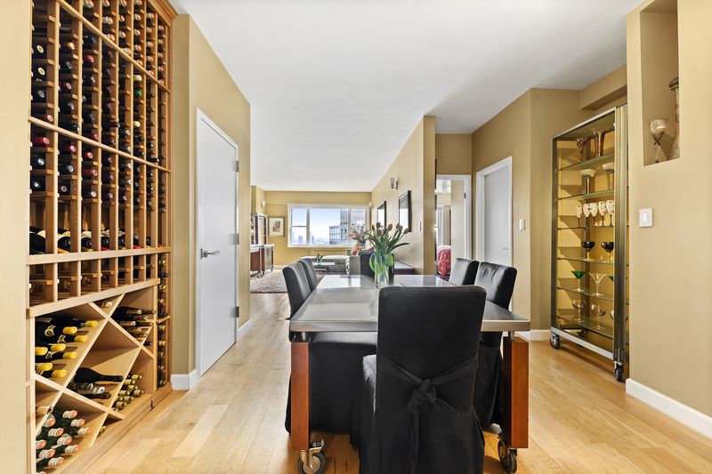 A living room with built-in wine storage, hardwood floors, and a dining table.