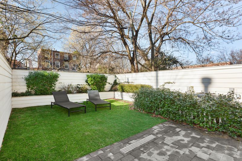 A backyard with shrubs and a white fence. 
