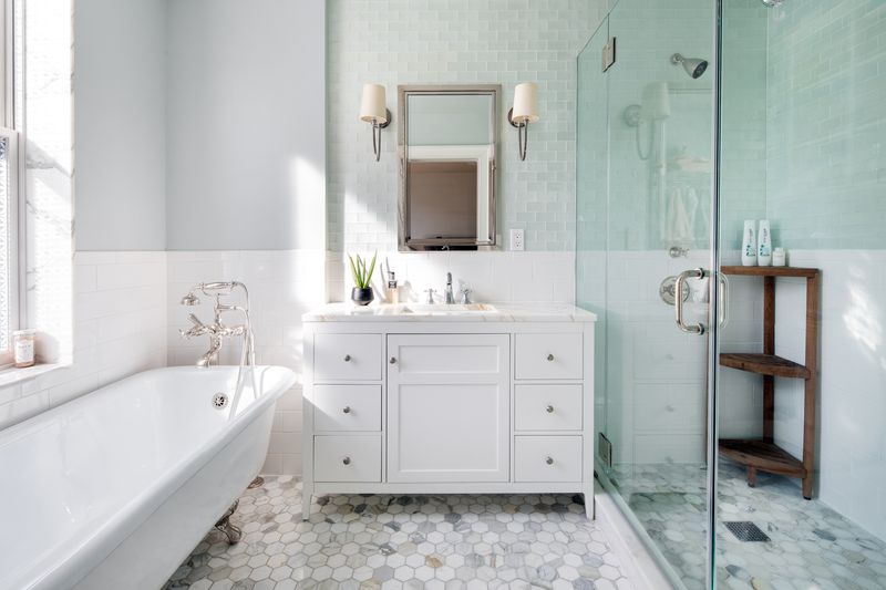 A bright bathroom attached to the master bedroom features a white clawfoot tub, single vanity, and glass enclosed shower.