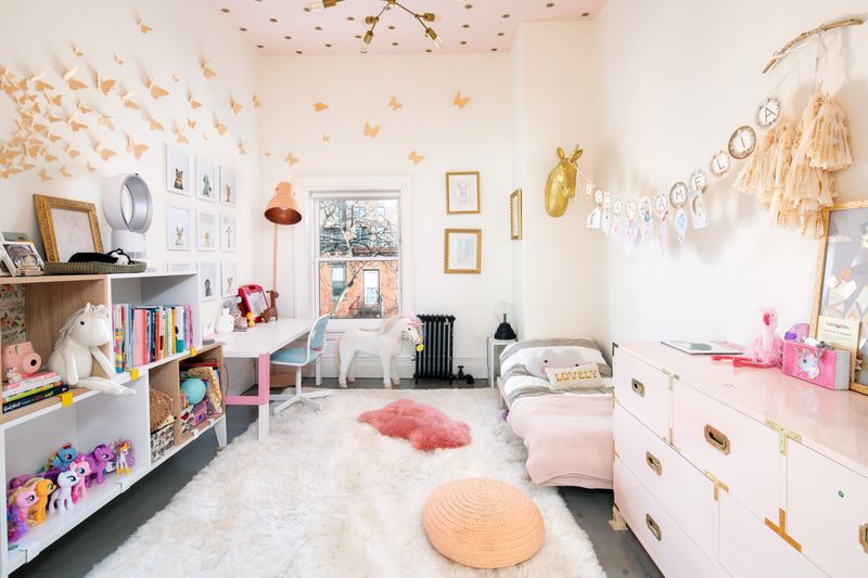 A top-floor kids room features high ceilings, a plush white area rug, and pink accents.