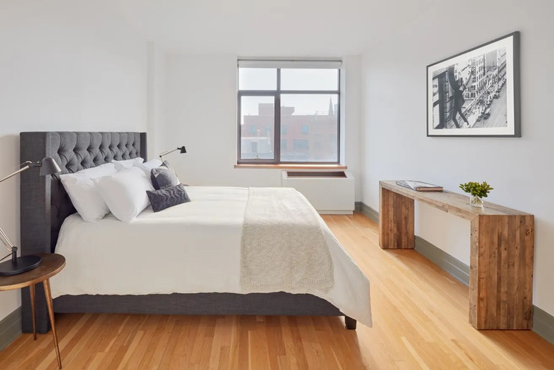 A bedroom with a large bed, a window, and hardwood floors.