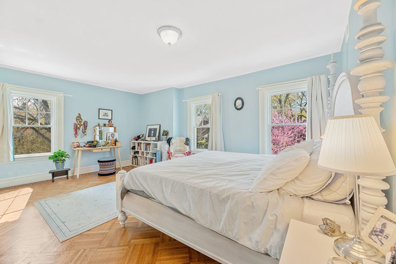 A bedroom with light blue walls, hardwood floors, and a small bed.