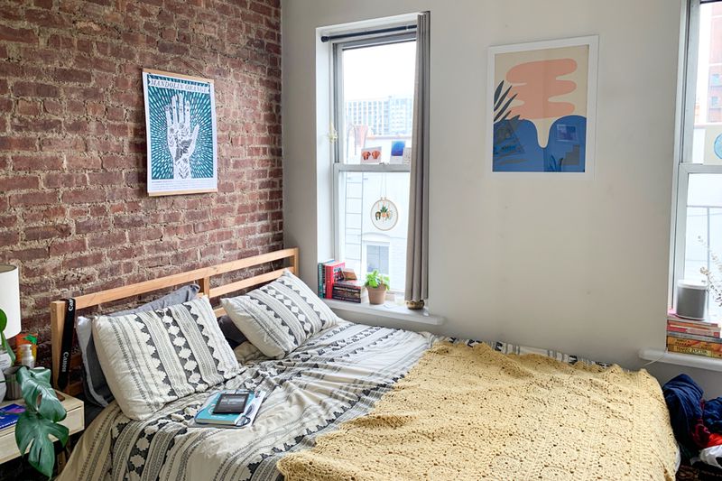 A bedroom with exposed brick, two windows, and a large bed.