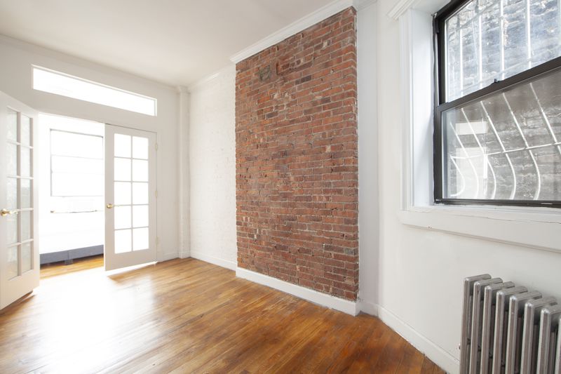 A living area with exposed brick, hardwood floors, and French doors.