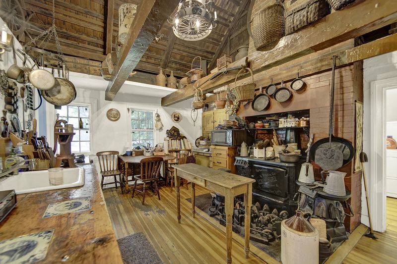 A country kitchen with vaulted ceilings, exposed brick, and pots and pans hanging from wood beams.