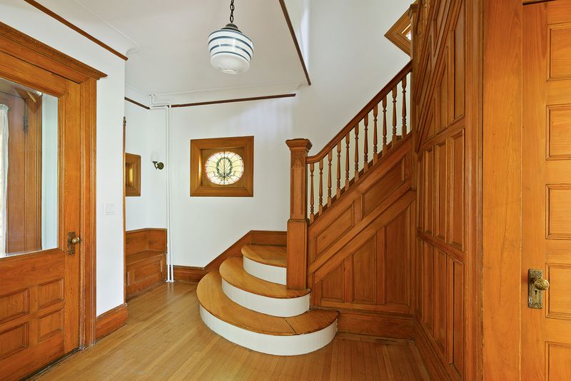 A foyer with oak wood details, a staircase, and stained glass windows.