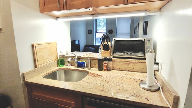 A kitchen’s counter with a sink and wooden cabinetry. 