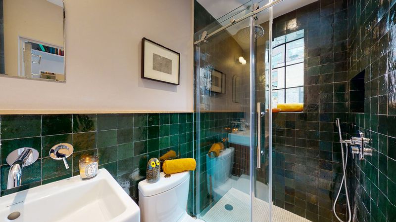 A bathroom with dark green tiles.