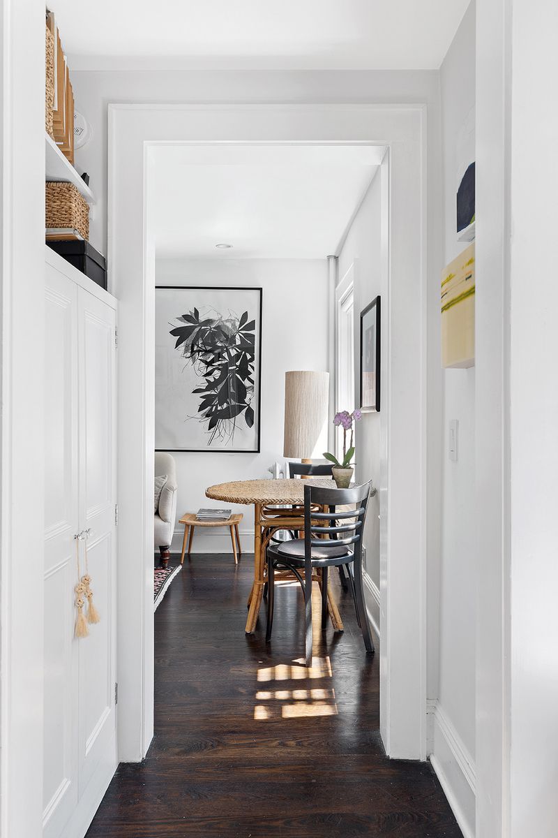 A hallway with hardwood floors, base moldings, and white cabinets.