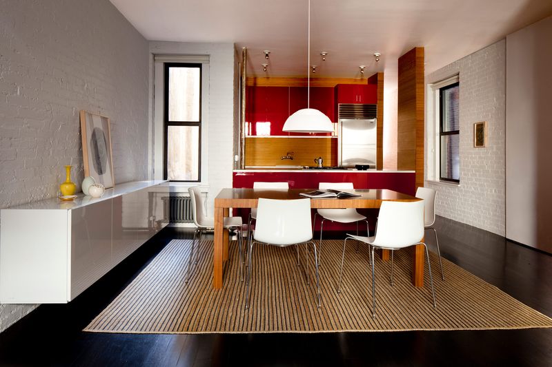 A view of the dining table with a red kitchen in the back.
