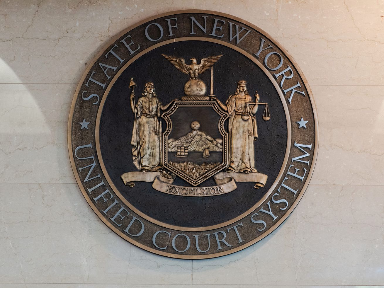 The seal of the State of New York Unified Court System hangs in the lobby of Kings County Supreme Court.